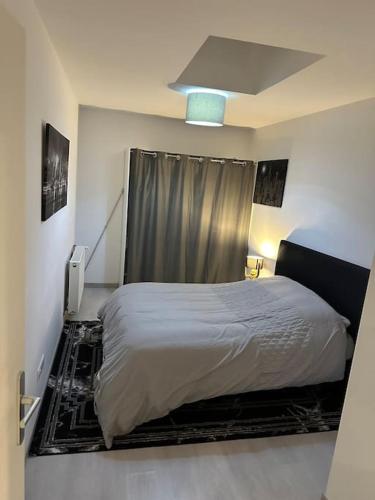 - une chambre avec un lit blanc et un rideau dans l'établissement Appartement cosy Nancy Bonsecours, à Jarville-la-Malgrange