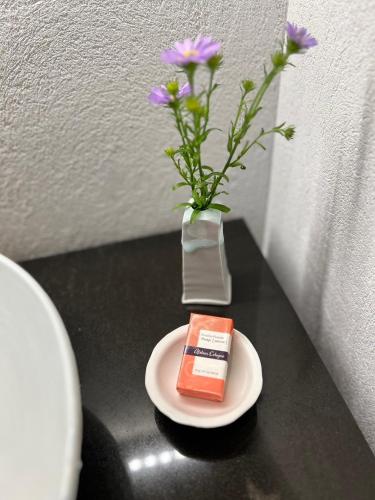 a table with a plate with a vase with purple flowers at 時地人 jijijin MATSUYAMA in Tobe