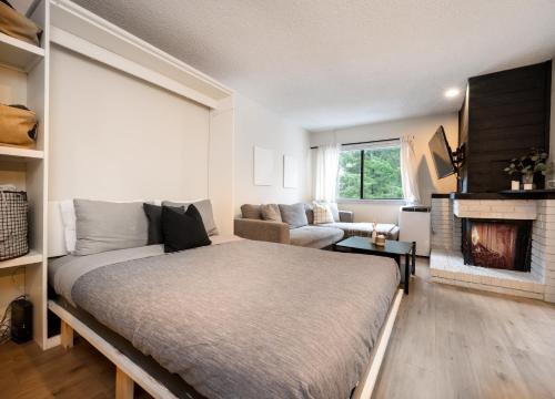 a living room with a bed and a fireplace at Creekside Oasis 4 Beds Pool and Hot Tub in Whistler
