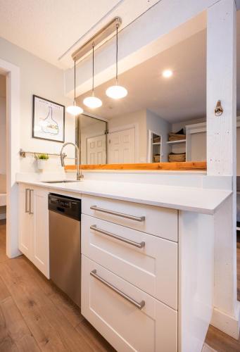 a kitchen with white cabinets and a sink at Creekside Oasis 4 Beds Pool and Hot Tub in Whistler