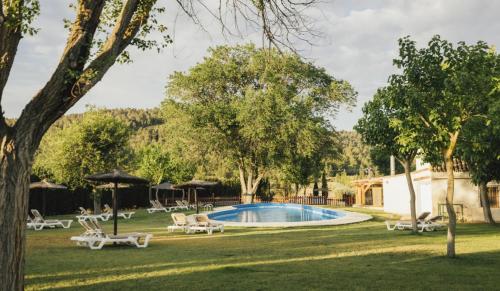 a pool in a yard with chairs and an umbrella at Camping Kikopark Rural in Villargordo del Cabriel