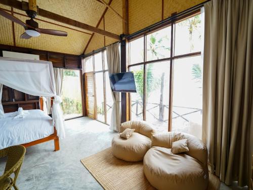 a bedroom with a bed and a chair and a large window at RoomQuest THEVA Resort Koh Samui in Koh Samui 