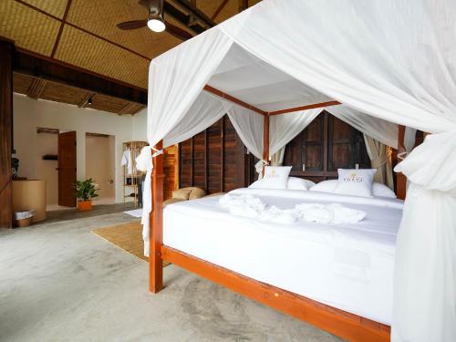 a bedroom with a large bed with white drapes at RoomQuest THEVA Resort Koh Samui in Koh Samui 