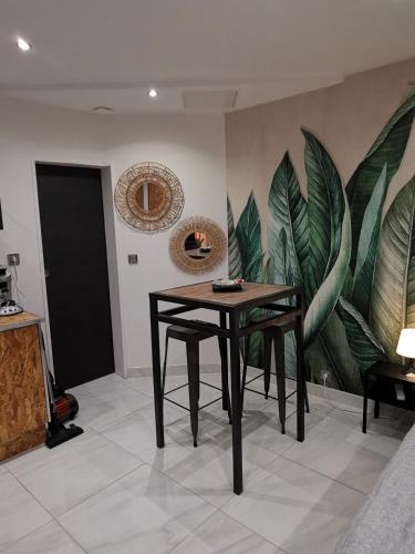 Cette chambre est dotée d'une table et d'une fresque murale représentant la plante. dans l'établissement Studio cosy proche Paris et Versailles, à Le Port-Marly