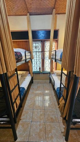 two bunk beds in a room with a window at Mai Family Guest House in Singaraja