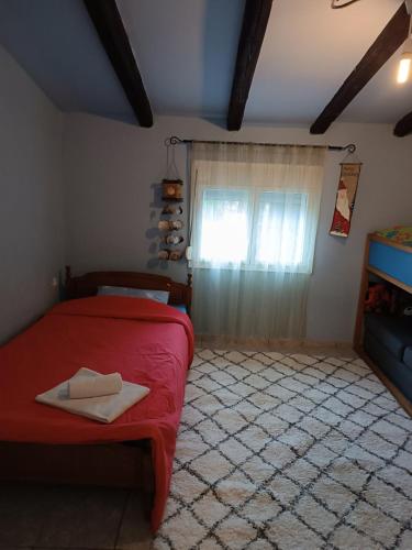 a bedroom with a red bed and a window at Cottage House in Kardítsa