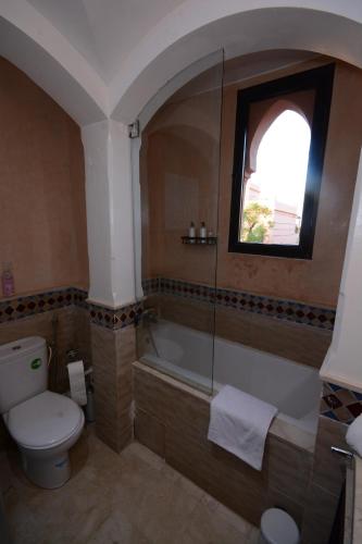 a bathroom with a toilet and a tub and a window at Maison d'Hôte Angele in Sfiani