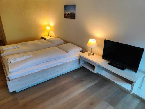a bedroom with a bed and a desk with a television at Hotel Säntis Lodge in Unterwasser