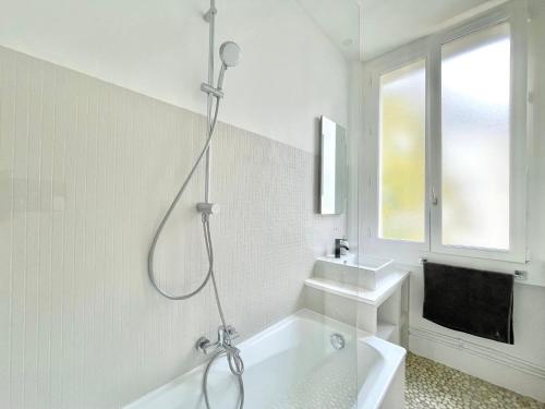 La salle de bains blanche est pourvue d'une douche et d'une baignoire. dans l'établissement Charming Apartment, Paris Centre, à Paris
