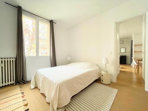 une chambre avec un lit blanc et une grande fenêtre dans l'établissement Charming Apartment, Paris Centre, à Paris