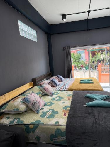 two twin beds in a room with a window at P'Un House in Ko Tao