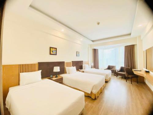 a hotel room with two beds and a desk at Muong Thanh Quy Nhon Hotel in Quy Nhon