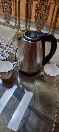 a tea kettle and two cups on a glass table at Sialkot International Airport Guesthouse in Sambriāl