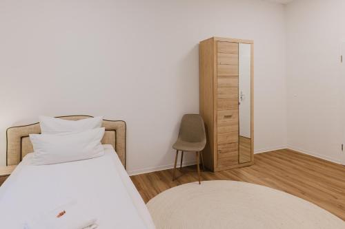 a bedroom with a bed and a chair and a mirror at Das MONTI - Comfort in Stendal