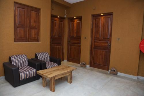 a living room with two chairs and a wooden table at Ceylon Ayu Resort Kandy in Kandy