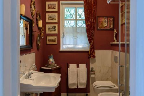 Un baño con lavabo, inodoro y ventana. en Villa Lucherina, en Stresa