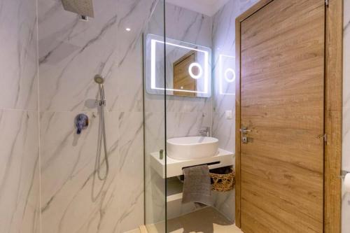 a bathroom with a shower with a sink and a mirror at Blue Sea Suites in Afitos