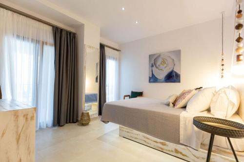 a white bedroom with a bed and a table and window at Blue Sea Suites in Afitos