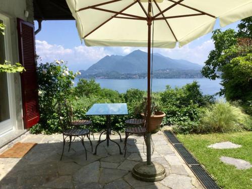 Una mesa y sillas bajo una sombrilla en un patio. en Villa Lucherina, en Stresa