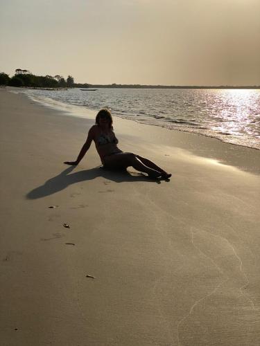 a woman sitting on the beach near the water at Oasis club in Cap Skirring
