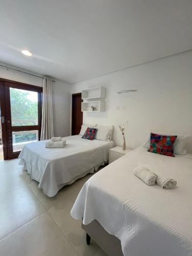 a bedroom with two beds and a window at Suites Amma Noronha in Fernando de Noronha