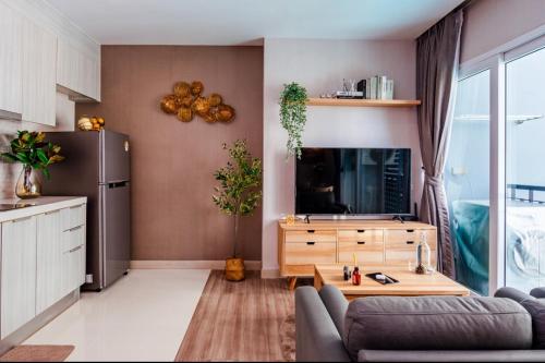 a living room with a couch and a tv and a table at Stay with Pano at The Prio Condo in Chiang Mai