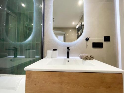 a bathroom with a sink and a shower with a mirror at Suite Émeraude centre ville in Sélestat