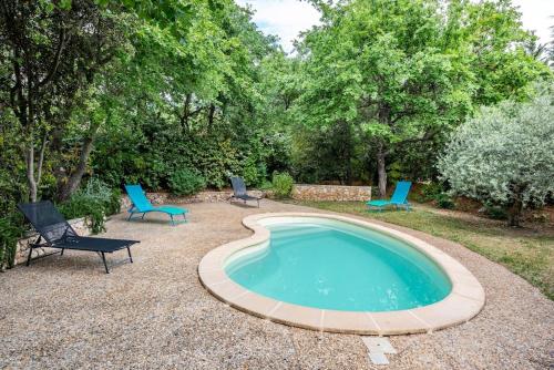 une piscine avec deux chaises et une table dans l'établissement Le cabanon, 3 étoiles, sa piscine au pied du Luberon, à Saint-Saturnin-lès-Apt