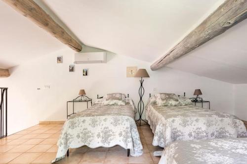 deux lits dans une chambre aux murs blancs dans l'établissement Le cabanon, 3 étoiles, sa piscine au pied du Luberon, à Saint-Saturnin-lès-Apt