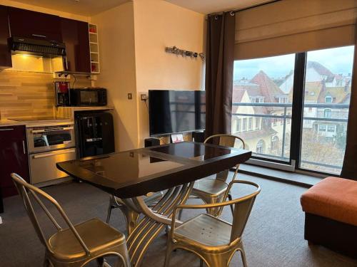 une cuisine avec une table et des chaises ainsi qu'une grande fenêtre dans l'établissement Appart Nausicaa en plein centre-ville, à Le Touquet-Paris-Plage