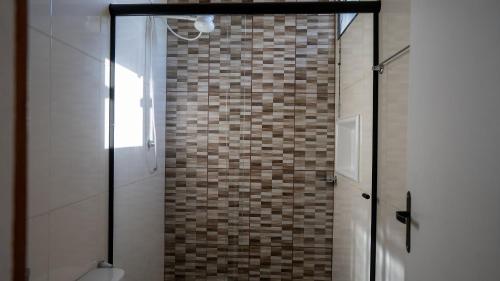 a bathroom with a shower with a tiled wall at Acesso à Praia Ar Condicionado Conforto Garantido! in Saquarema