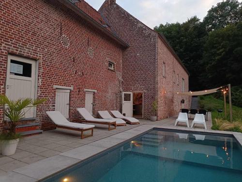 a swimming pool with lounge chairs next to a brick building at La Canopée des Arbres, Anna in Ellezelles