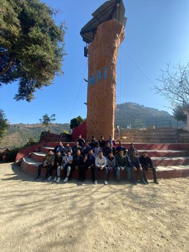 a group of people posing for a picture in front of a tower at The Himalaya Retreat Resort, Experience Nature in the Lap of Himalayas in Mussoorie