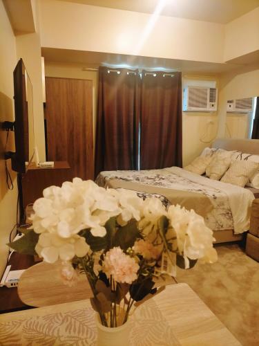 a bedroom with a bed and a table with a vase of flowers at Avida Towers Riala, Tower 2 in Cebu City
