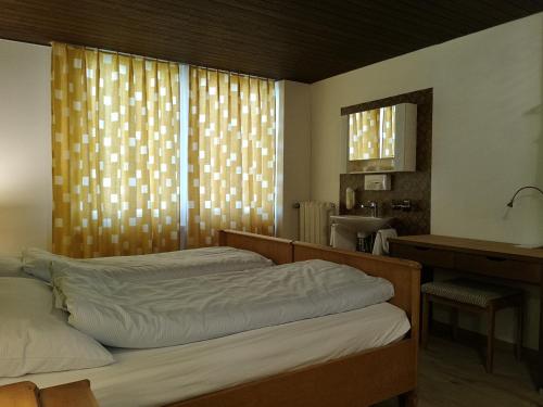 a bedroom with two beds and a desk and a window at Gasthaus Friedegg in Wildhaus