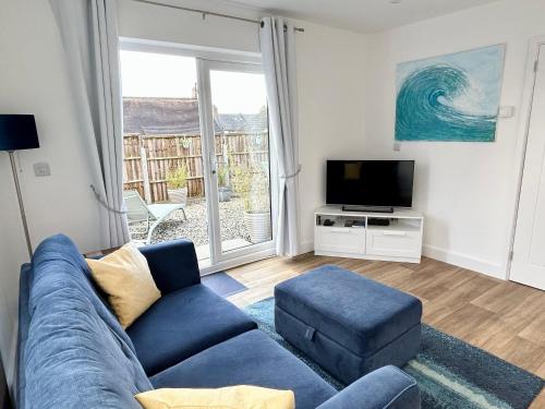 a living room with a blue couch and a tv at Hightide in Bude