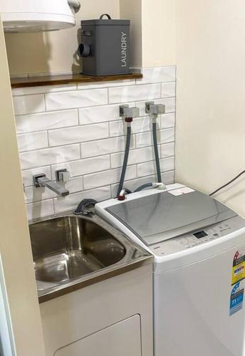 a small kitchen with a sink and a washing machine at CBD Esplanade Location - Quiet & Comfortable in Darwin