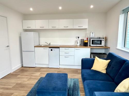 a living room with a blue couch and a kitchen at Hightide in Bude