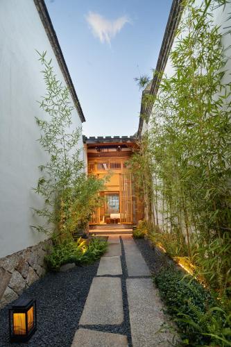 a walkway leading into a house with trees at 福州三坊七巷安民半舍文化酒店Fuzhou Sanfang Qixiang Anmin Banshe Cultural Hotel in Fuzhou