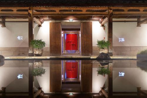 a building with red doors and a pool of water at 福州三坊七巷安民半舍文化酒店Fuzhou Sanfang Qixiang Anmin Banshe Cultural Hotel in Fuzhou