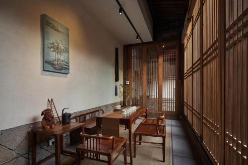 福州福州三坊七巷安民半舍文化酒店Fuzhou Sanfang Qixiang Anmin Banshe Cultural Hotel的大楼内带木桌和椅子的房间