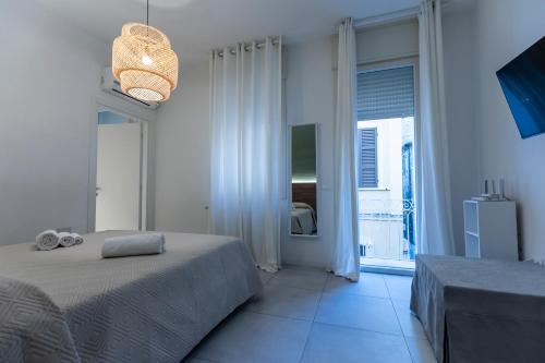 a white bedroom with a bed and a large window at Dantis Rooms in Ravenna