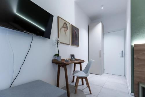 a room with a desk and a television on a wall at Dantis Rooms in Ravenna