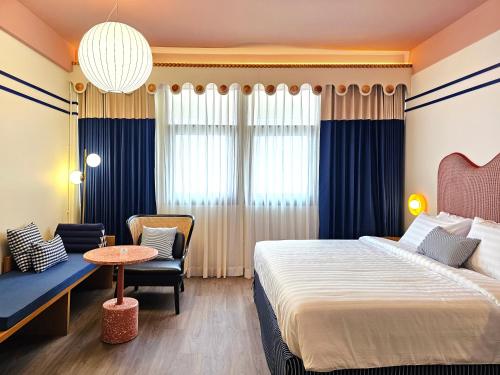 a hotel room with a bed and a chair and a table at Blu Dock Restel Bangkok in Bangkok