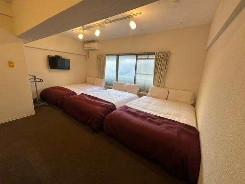 a group of three beds in a room at Nagai park side stay premium in Osaka