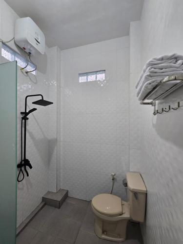 a white bathroom with a toilet and a shower at Achazia Homestay in Labuan Bajo