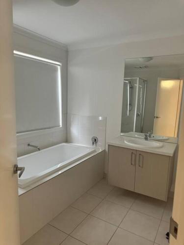 a white bathroom with a tub and a sink at The Blissful Abode in Truganina