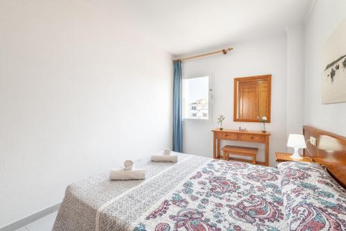 a bedroom with a bed and a desk and a window at C'an Vidal apto Menorca in Colonia Sant Jordi