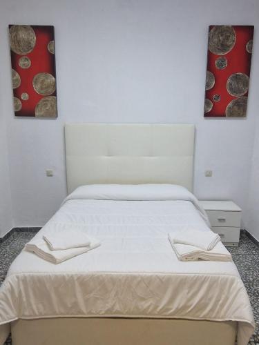 una camera da letto con un letto bianco e due dipinti alle pareti di Casa Amador a Hinojosa del Duque