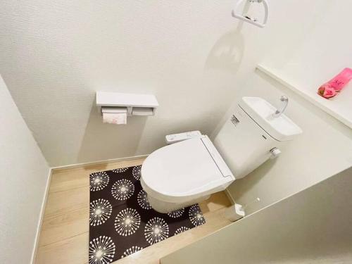 a bathroom with a toilet and a black and white rug at 海に近い田舎にある新築家の丹霞阁 in Itoman
